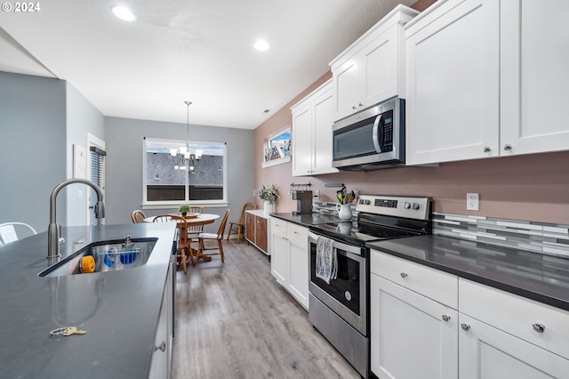 kitchen with sink, hanging light fixtures, light hardwood / wood-style floors, white cabinets, and appliances with stainless steel finishes