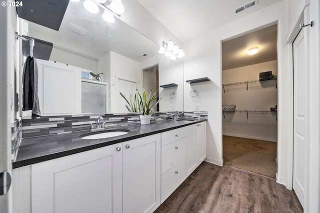 bathroom featuring vanity, backsplash, wood-type flooring, and walk in shower