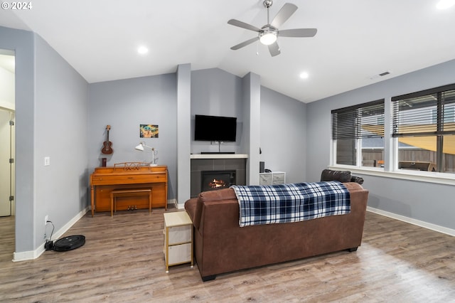 living room featuring lofted ceiling, hardwood / wood-style floors, a fireplace, and ceiling fan