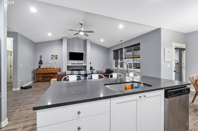 kitchen featuring stainless steel dishwasher, ceiling fan, sink, white cabinets, and an island with sink