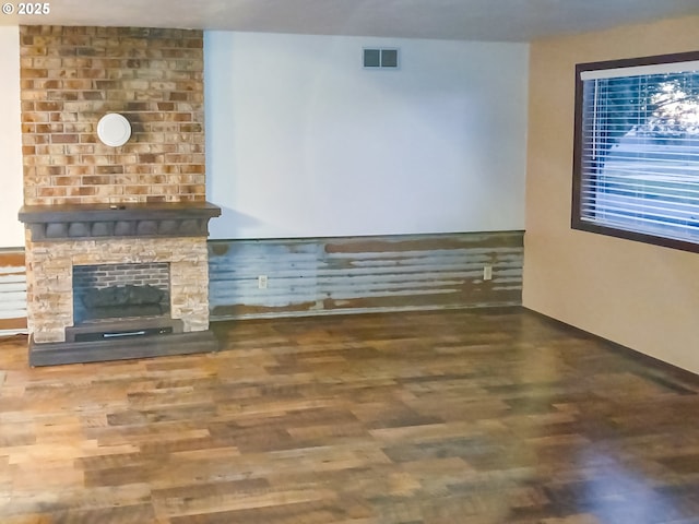 unfurnished living room featuring a large fireplace and dark wood-type flooring