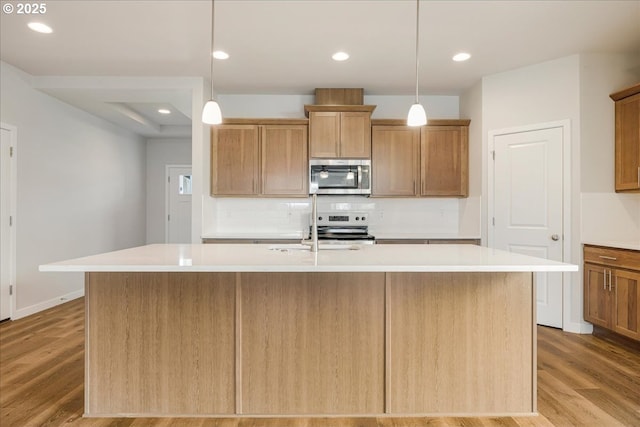 kitchen featuring sink, a center island with sink, hanging light fixtures, and appliances with stainless steel finishes