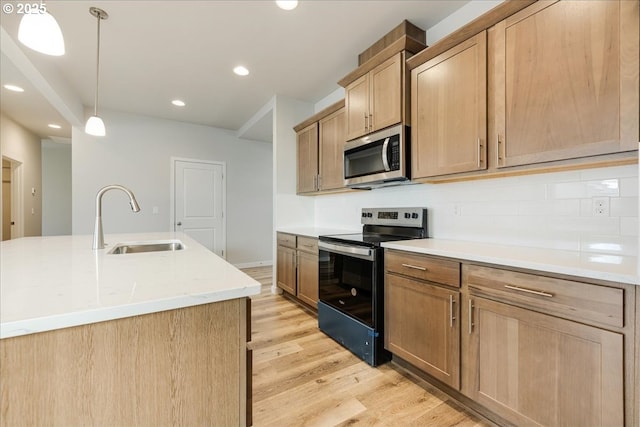 kitchen with sink, hanging light fixtures, an island with sink, and appliances with stainless steel finishes