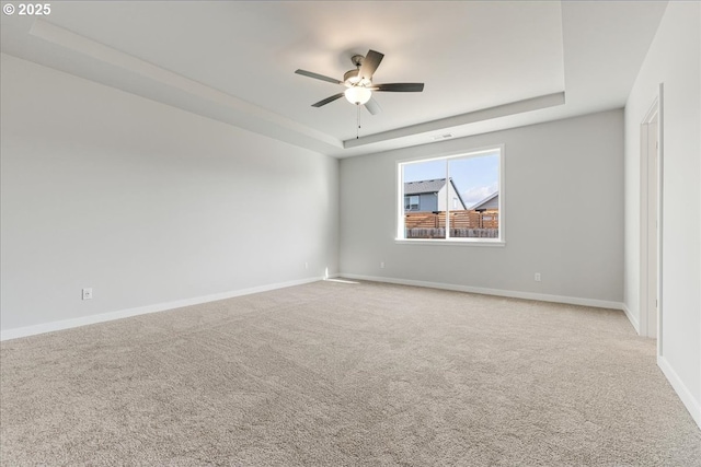 carpeted spare room featuring a raised ceiling and ceiling fan