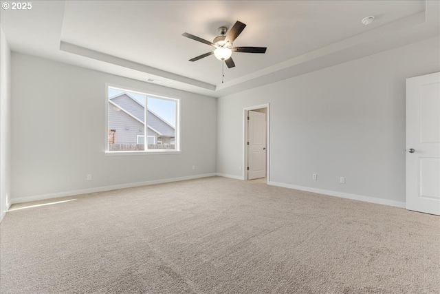 carpeted spare room featuring ceiling fan and a raised ceiling