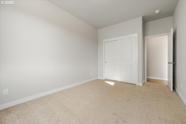 unfurnished bedroom with light colored carpet and a closet