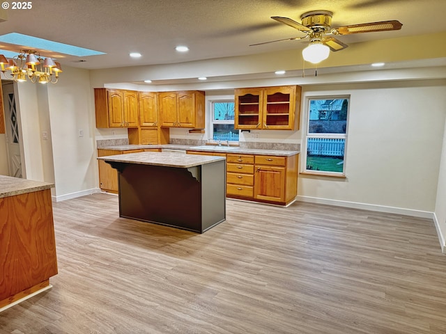 kitchen with sink, light hardwood / wood-style floors, a kitchen island, and a textured ceiling