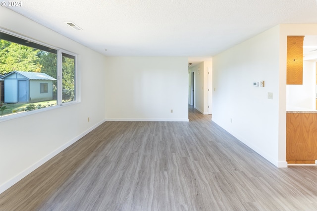 unfurnished room with a textured ceiling and light wood-type flooring