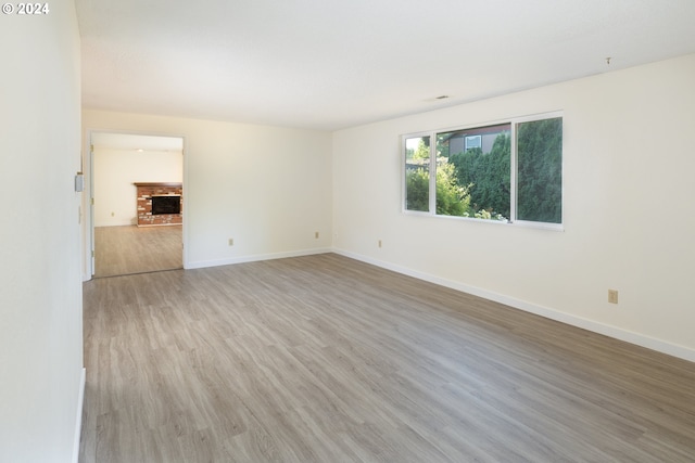 unfurnished room with a brick fireplace and hardwood / wood-style floors