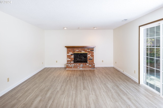 unfurnished living room with a fireplace, a textured ceiling, and light wood-type flooring