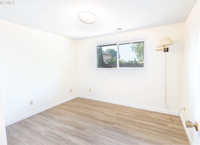 unfurnished room featuring light hardwood / wood-style flooring and a textured ceiling