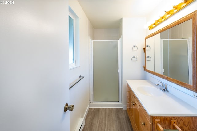 bathroom featuring hardwood / wood-style flooring, vanity, an enclosed shower, and a baseboard heating unit