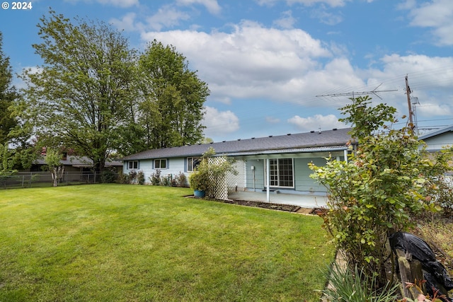 rear view of property featuring a lawn and a patio