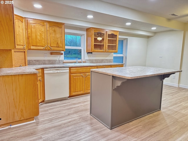 kitchen with sink, a breakfast bar area, dishwasher, a kitchen island, and light hardwood / wood-style floors