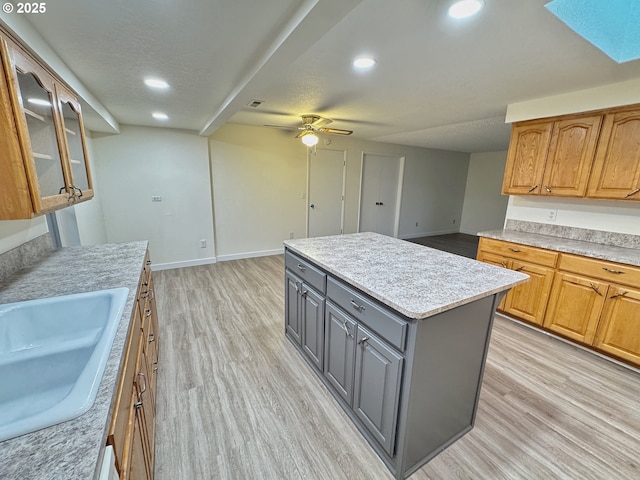 kitchen featuring sink, gray cabinetry, a center island, a textured ceiling, and light wood-type flooring