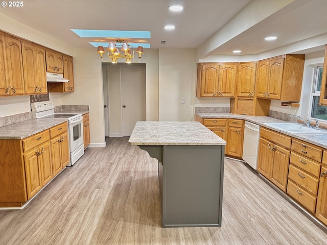 kitchen featuring sink, white appliances, light hardwood / wood-style flooring, a skylight, and a center island