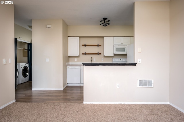 kitchen featuring white appliances, washer and clothes dryer, dark carpet, and white cabinets