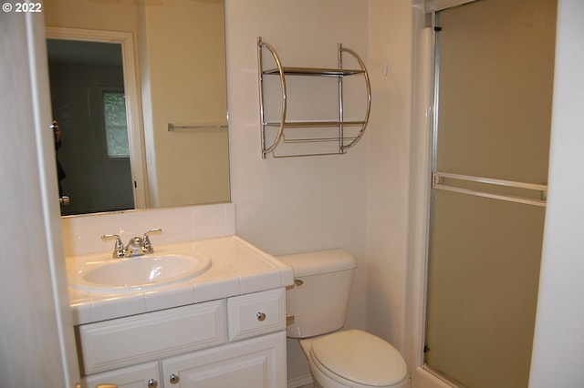 bathroom featuring a shower with door, vanity, and toilet