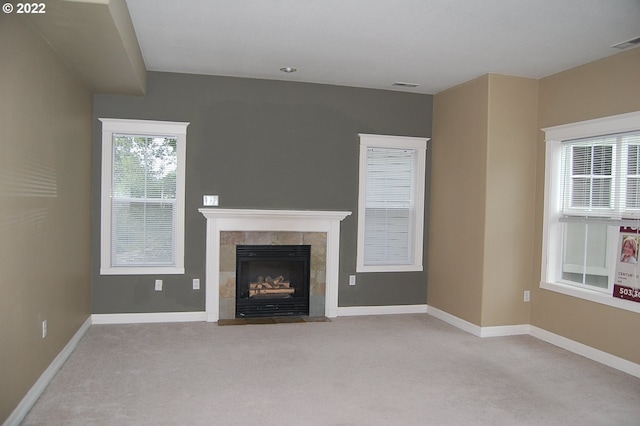 unfurnished living room with a tiled fireplace and light colored carpet