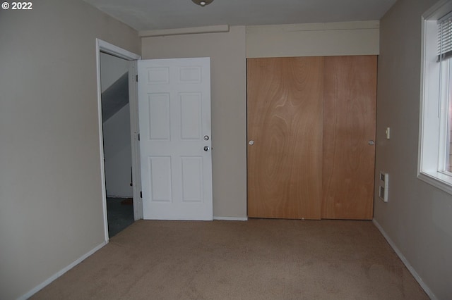 unfurnished bedroom with light colored carpet and a closet