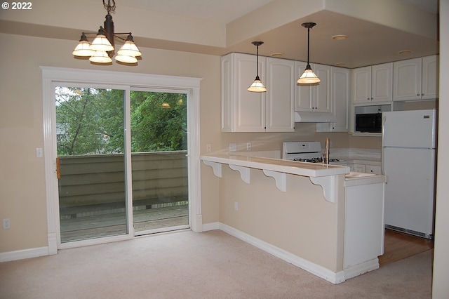 kitchen with a breakfast bar area, kitchen peninsula, white cabinetry, and white refrigerator