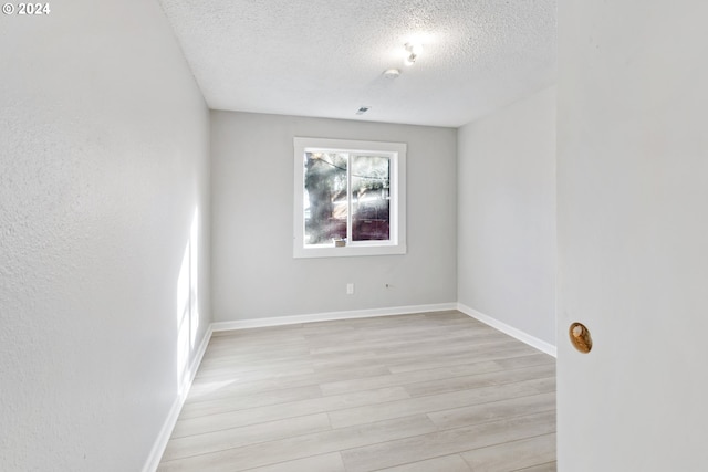 spare room with light wood-type flooring and a textured ceiling