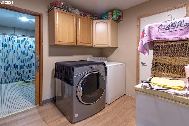 laundry room with cabinets, light hardwood / wood-style flooring, and washing machine and clothes dryer