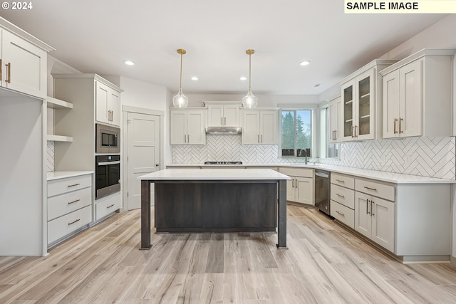 kitchen featuring a kitchen bar, stainless steel appliances, decorative light fixtures, and light wood-type flooring