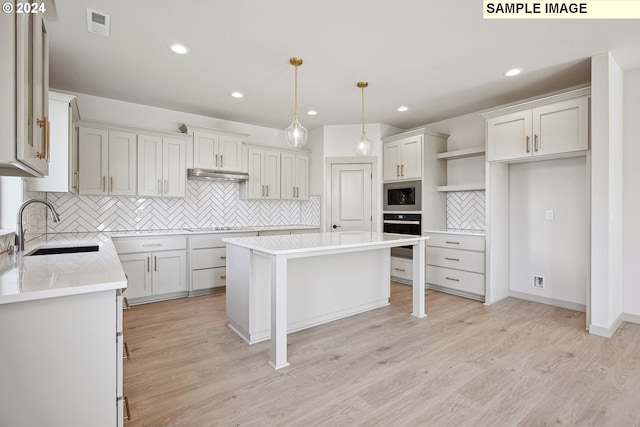 kitchen with sink, a kitchen island, light wood-type flooring, and appliances with stainless steel finishes