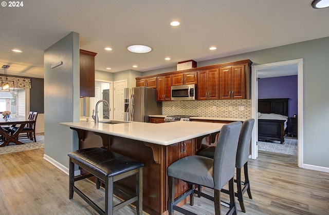 kitchen with stainless steel appliances, sink, light wood-type flooring, and kitchen peninsula