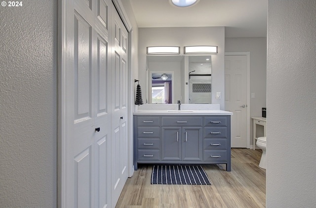 bathroom with toilet, vanity, hardwood / wood-style floors, and walk in shower