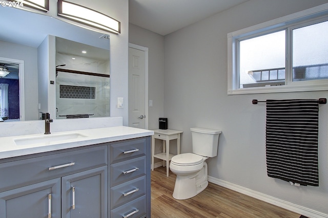 bathroom with hardwood / wood-style floors, a shower with shower door, vanity, and toilet