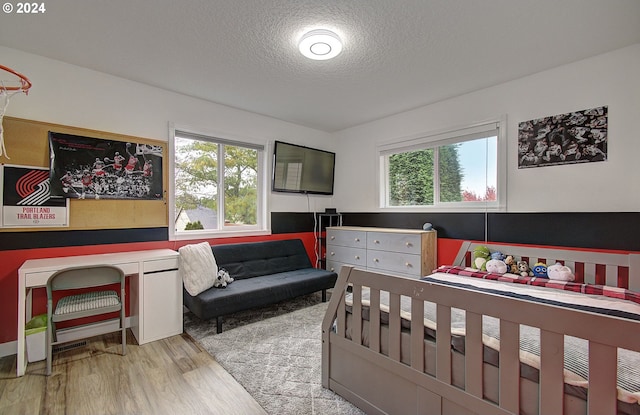 bedroom with multiple windows, a textured ceiling, and light hardwood / wood-style floors