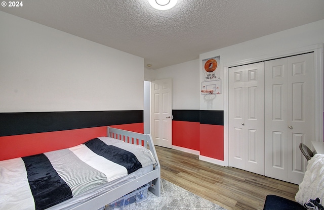 bedroom with hardwood / wood-style floors, a textured ceiling, and a closet