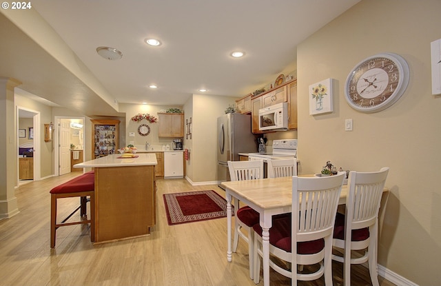 kitchen featuring white appliances, light hardwood / wood-style floors, and a center island