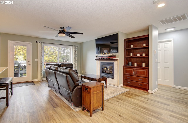 living room featuring a textured ceiling, light hardwood / wood-style flooring, and ceiling fan