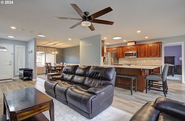 living room with ceiling fan with notable chandelier and light wood-type flooring