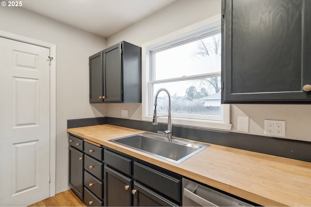 kitchen featuring dishwasher, light hardwood / wood-style floors, sink, and wooden counters