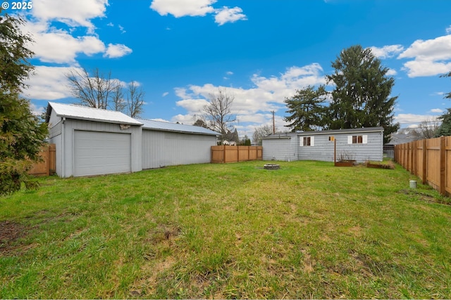 view of yard with an outbuilding, a fire pit, and a garage