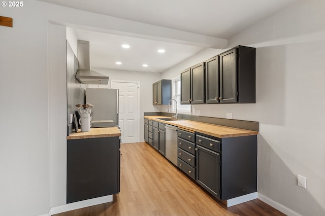 kitchen featuring exhaust hood, sink, appliances with stainless steel finishes, light hardwood / wood-style floors, and butcher block counters