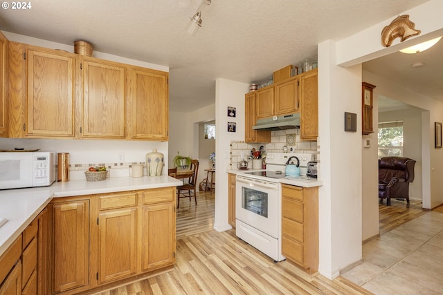 kitchen featuring a textured ceiling, light wood-type flooring, white appliances, and decorative backsplash