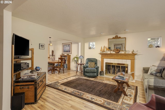 living room with a fireplace, a textured ceiling, and light hardwood / wood-style floors