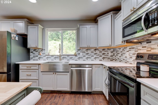 kitchen featuring sink, dark hardwood / wood-style floors, tasteful backsplash, stainless steel appliances, and white cabinets