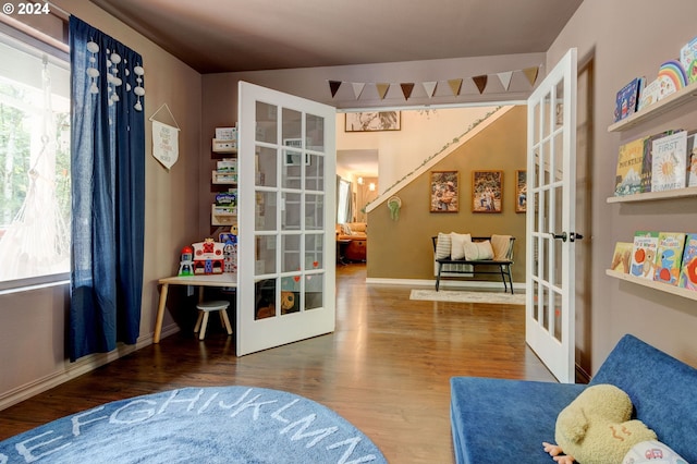 sitting room featuring baseboards, french doors, wood finished floors, and a healthy amount of sunlight