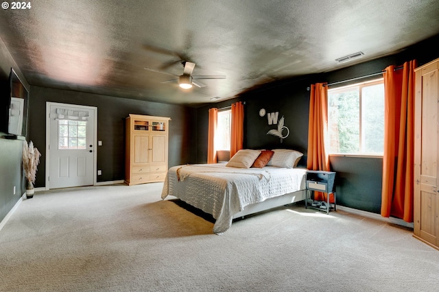 bedroom with visible vents, light carpet, and a textured ceiling