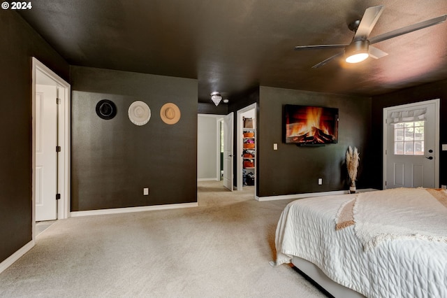 bedroom featuring light carpet, baseboards, a ceiling fan, a walk in closet, and a closet