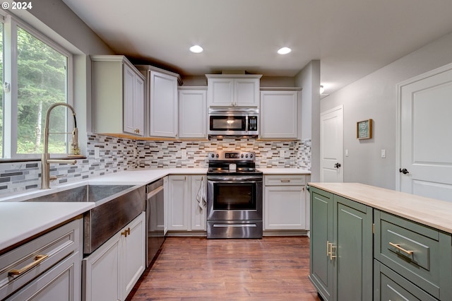 kitchen featuring white cabinets, stainless steel appliances, light countertops, and wood finished floors