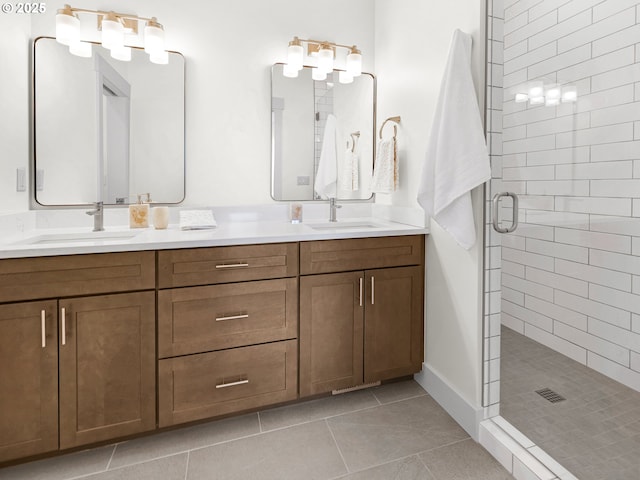bathroom featuring double vanity, a shower stall, tile patterned flooring, and a sink