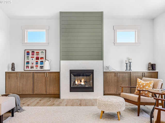 living area featuring light wood-style floors, a wealth of natural light, and a glass covered fireplace