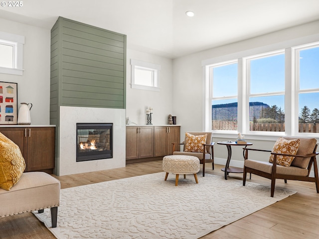 living area with recessed lighting, a glass covered fireplace, and light wood finished floors